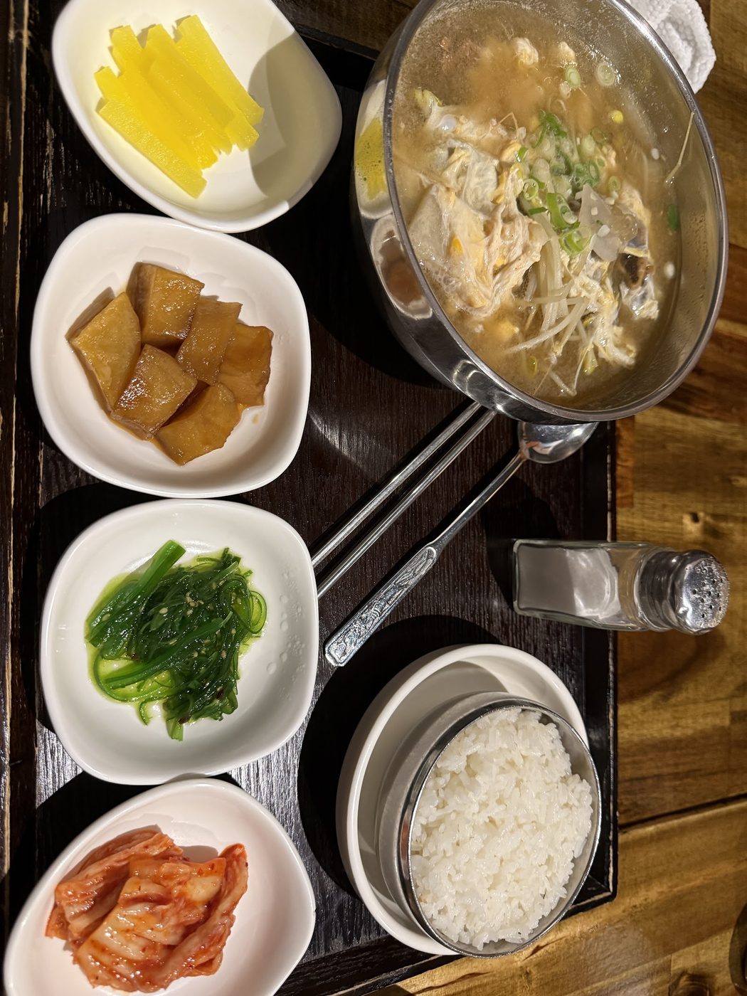 Pale broth with egg, bean sprouts and spring onion in a shallow steel pot
